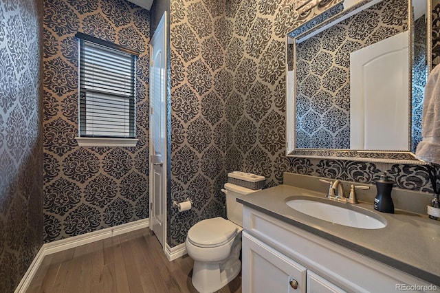 14589 Hagus Pl, Parker, CO 80134 - bathroom featuring hardwood / wood-style flooring, wallpapered walls, baseboards, toilet, and vanity