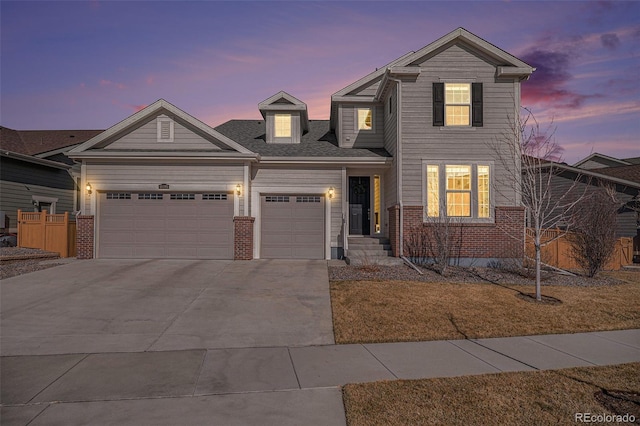 traditional home with a garage, brick siding, driveway, and fence