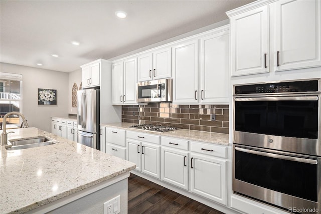 kitchen featuring a sink, decorative backsplash, dark wood-type flooring, appliances with stainless steel finishes, and white cabinetry