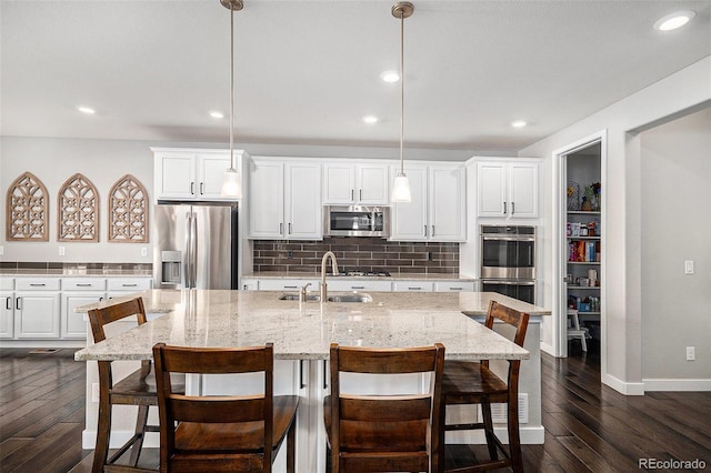 kitchen featuring dark wood finished floors, decorative backsplash, stainless steel appliances, and a sink