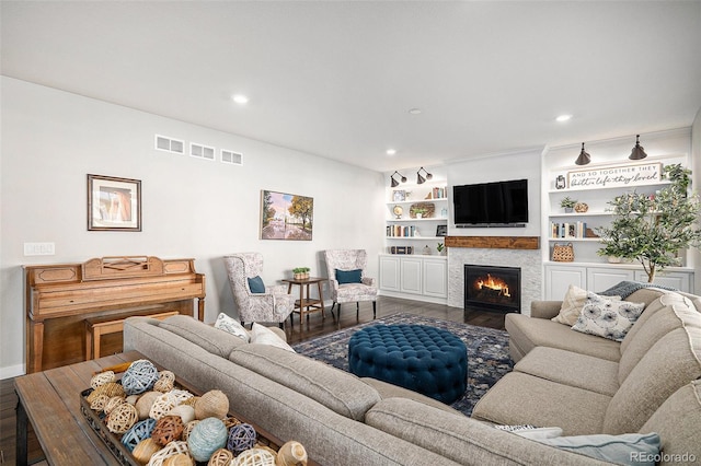 living room featuring recessed lighting, wood finished floors, visible vents, and a warm lit fireplace