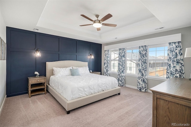 bedroom featuring a tray ceiling, light carpet, visible vents, and ceiling fan