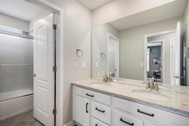 full bathroom with a sink, enclosed tub / shower combo, wood finished floors, and double vanity