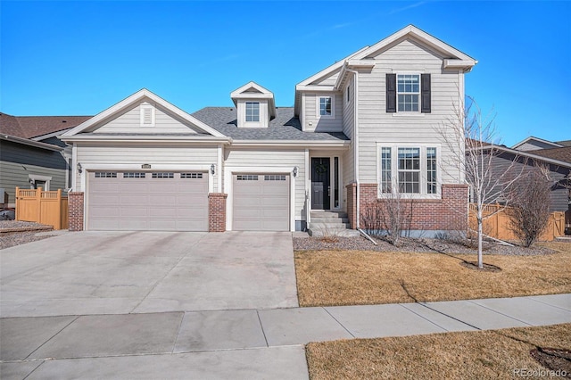 traditional home with a garage, brick siding, concrete driveway, and fence