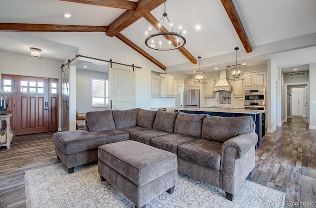 living room with vaulted ceiling with beams, light wood-type flooring, an inviting chandelier, and a barn door