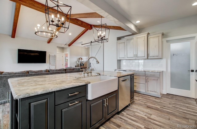 kitchen featuring light hardwood / wood-style flooring, backsplash, pendant lighting, lofted ceiling with beams, and a center island with sink