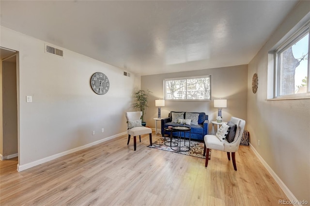 sitting room featuring a healthy amount of sunlight, visible vents, and light wood-style flooring