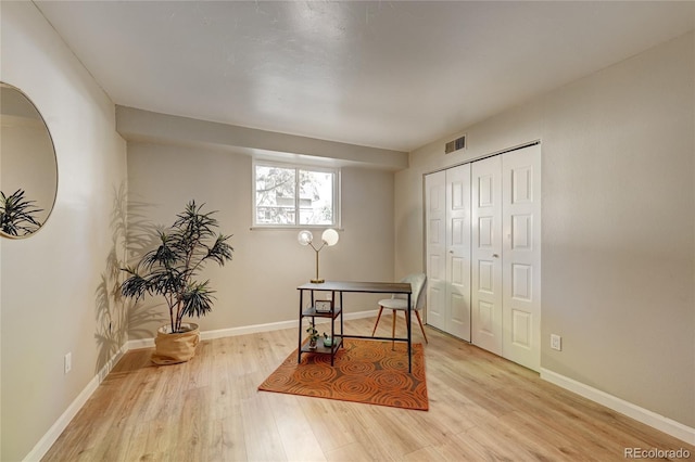 home office featuring light wood finished floors, baseboards, and visible vents