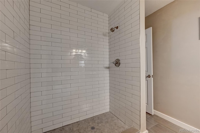 bathroom with baseboards and a tile shower