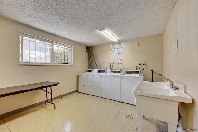 community laundry room with baseboards, a sink, washer and clothes dryer, and a textured ceiling