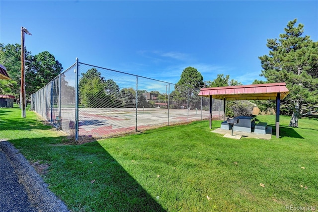 view of community with a tennis court, fence, and a lawn