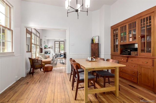 1776 S Logan St, Denver, CO 80210 - dining space featuring light wood finished floors, wainscoting, a chandelier, a fireplace, and a towering ceiling