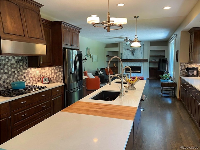 kitchen with fridge with ice dispenser, stainless steel gas cooktop, a sink, light countertops, and open floor plan