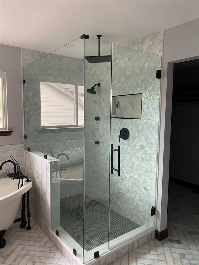 bathroom featuring tile walls, a stall shower, a freestanding tub, and a wealth of natural light