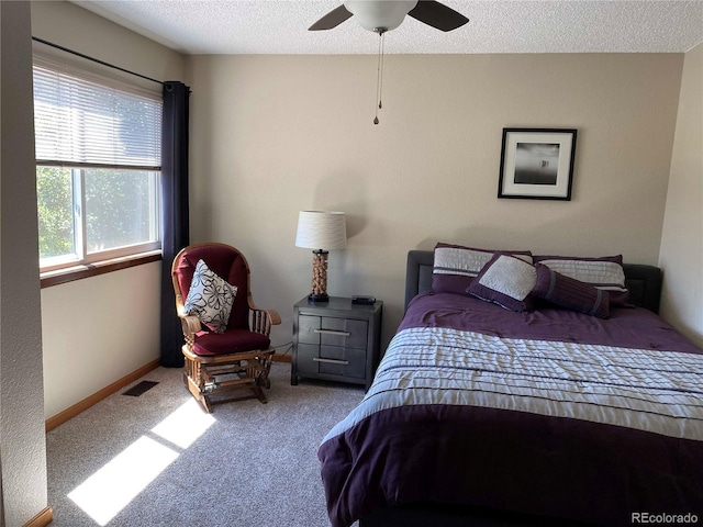 bedroom featuring ceiling fan, a textured ceiling, visible vents, carpet floors, and baseboards