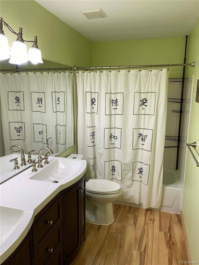 full bath with visible vents, shower / tub combo, toilet, vanity, and wood finished floors