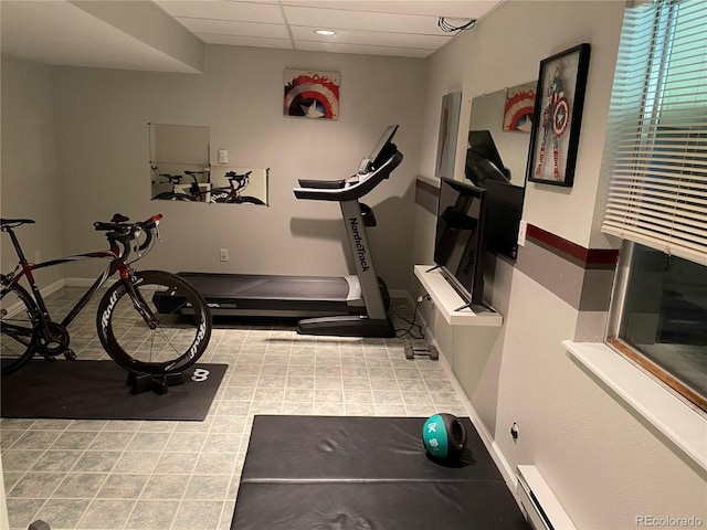exercise room with a baseboard heating unit, baseboards, and a drop ceiling