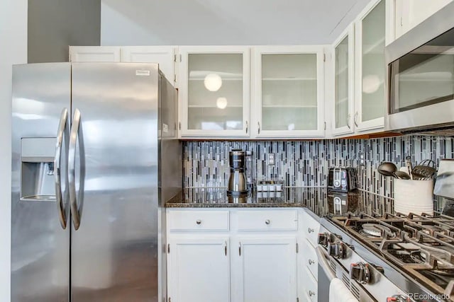 6365 Xavier Ct, Arvada, CO 80003 - kitchen with appliances with stainless steel finishes, white cabinets, dark stone counters, glass insert cabinets, and tasteful backsplash