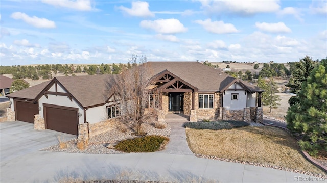 tudor home with an attached garage, stone siding, concrete driveway, and stucco siding