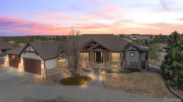 view of front of property featuring stone siding, driveway, an attached garage, and stucco siding