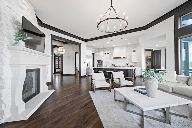 living area featuring baseboards, dark wood finished floors, a fireplace with raised hearth, crown molding, and recessed lighting