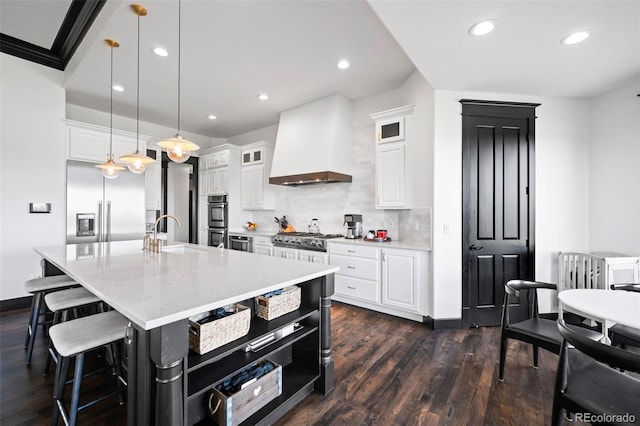 kitchen with tasteful backsplash, dark wood finished floors, custom exhaust hood, stainless steel appliances, and a sink