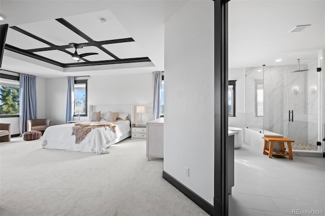 bedroom with a raised ceiling, light colored carpet, and ensuite bathroom