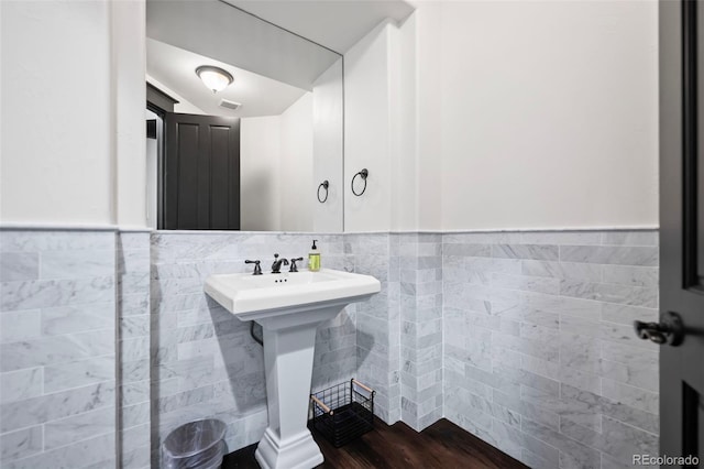 bathroom featuring visible vents, a wainscoted wall, a sink, and tile walls