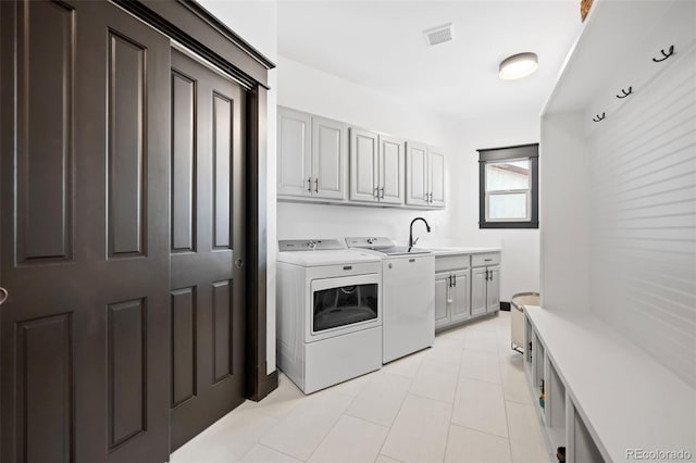 laundry area with light tile patterned floors, cabinet space, visible vents, a sink, and separate washer and dryer