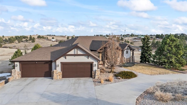 view of front of house featuring an attached garage, stone siding, driveway, roof with shingles, and stucco siding