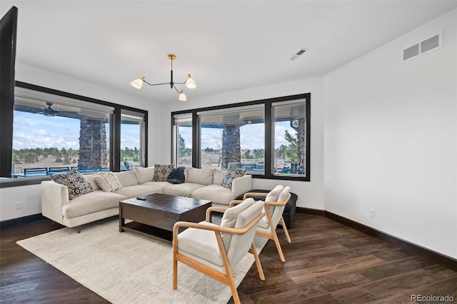 living area featuring a chandelier, dark wood-type flooring, visible vents, and baseboards