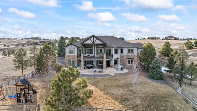 back of house featuring stone siding, a patio, and fence