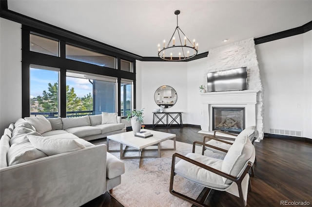 living area featuring crown molding, visible vents, a stone fireplace, wood finished floors, and baseboards