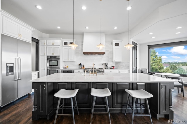 kitchen featuring stainless steel appliances, backsplash, white cabinetry, a sink, and premium range hood