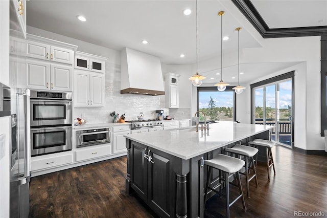 kitchen featuring appliances with stainless steel finishes, a sink, white cabinets, and custom range hood