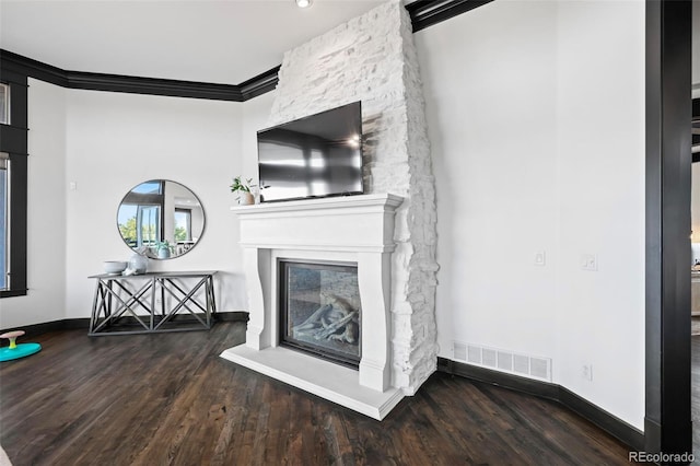 unfurnished living room with a fireplace, wood finished floors, visible vents, baseboards, and crown molding