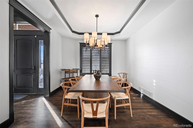 dining space featuring a notable chandelier, wood finished floors, visible vents, baseboards, and a tray ceiling