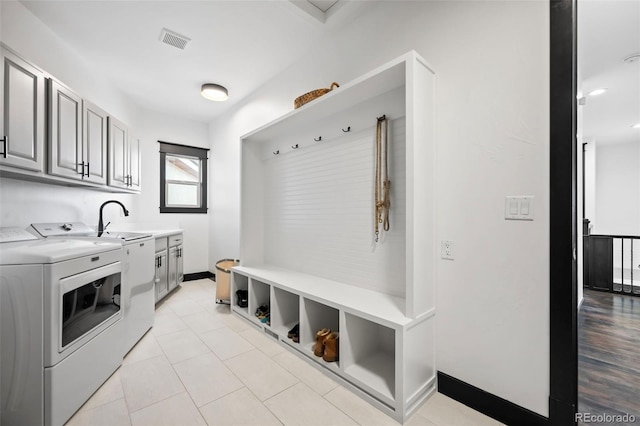 mudroom featuring light tile patterned floors, a sink, visible vents, baseboards, and washer and dryer