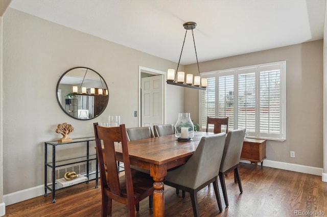 dining space with baseboards, an inviting chandelier, and wood finished floors
