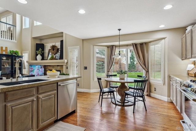 kitchen with baseboards, light wood-type flooring, appliances with stainless steel finishes, and a sink