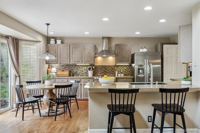 kitchen with wall chimney exhaust hood, a wealth of natural light, light wood-style flooring, and appliances with stainless steel finishes