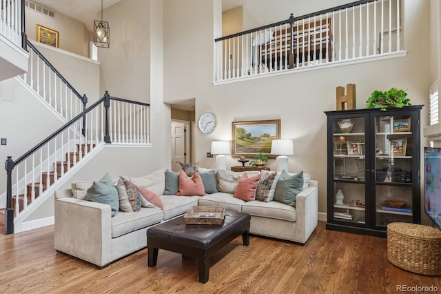 living room featuring visible vents, wood finished floors, a high ceiling, and stairway