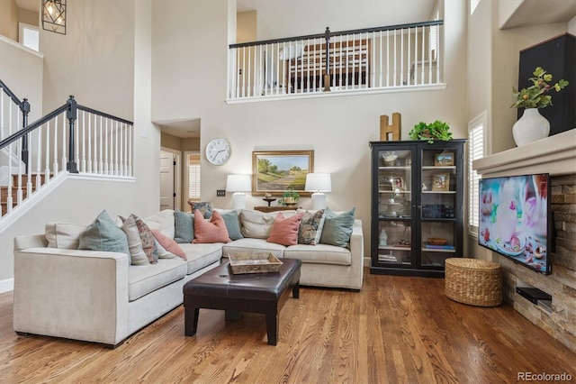 living room with stairway, a towering ceiling, and wood finished floors