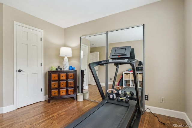 workout area featuring baseboards and wood finished floors