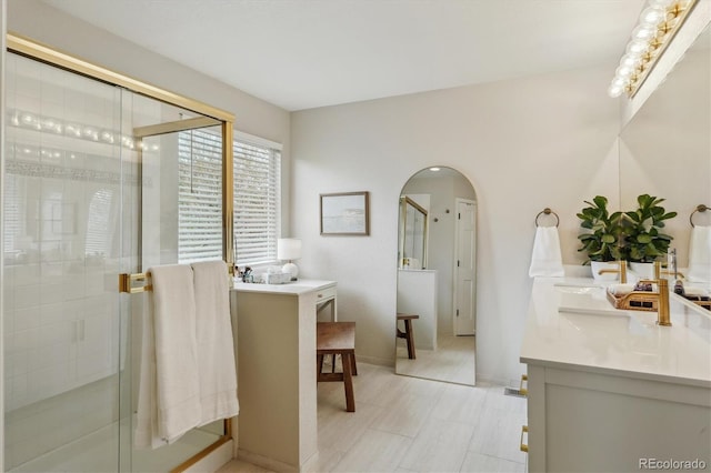 bathroom featuring a stall shower, baseboards, and double vanity