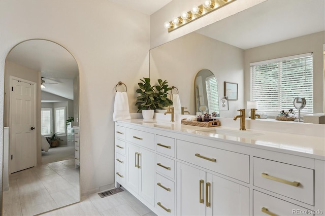 ensuite bathroom with a sink, ceiling fan, connected bathroom, and double vanity
