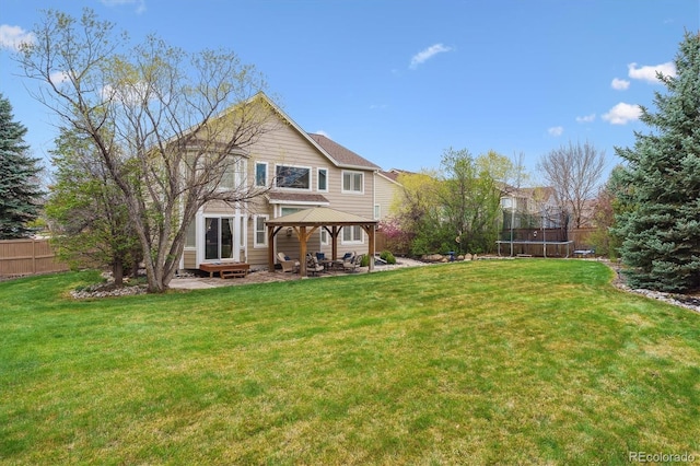 rear view of house with a gazebo, fence, a trampoline, a patio, and a lawn