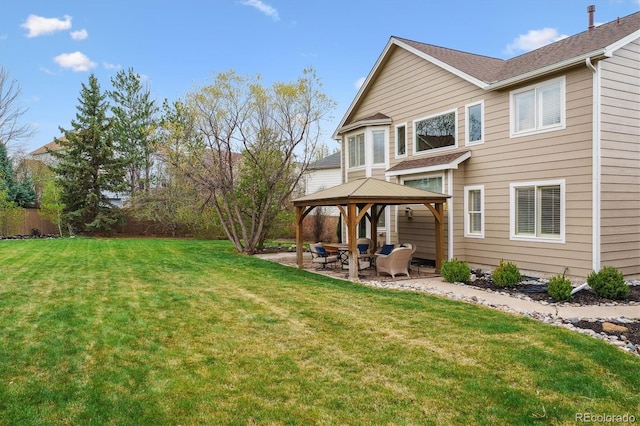 rear view of house featuring a lawn, fence, a patio, a gazebo, and roof with shingles