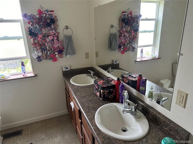 bathroom featuring tile patterned flooring, double sink vanity, toilet, and a wealth of natural light