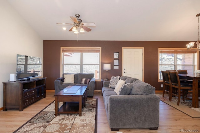 living room with ceiling fan with notable chandelier and light wood-type flooring